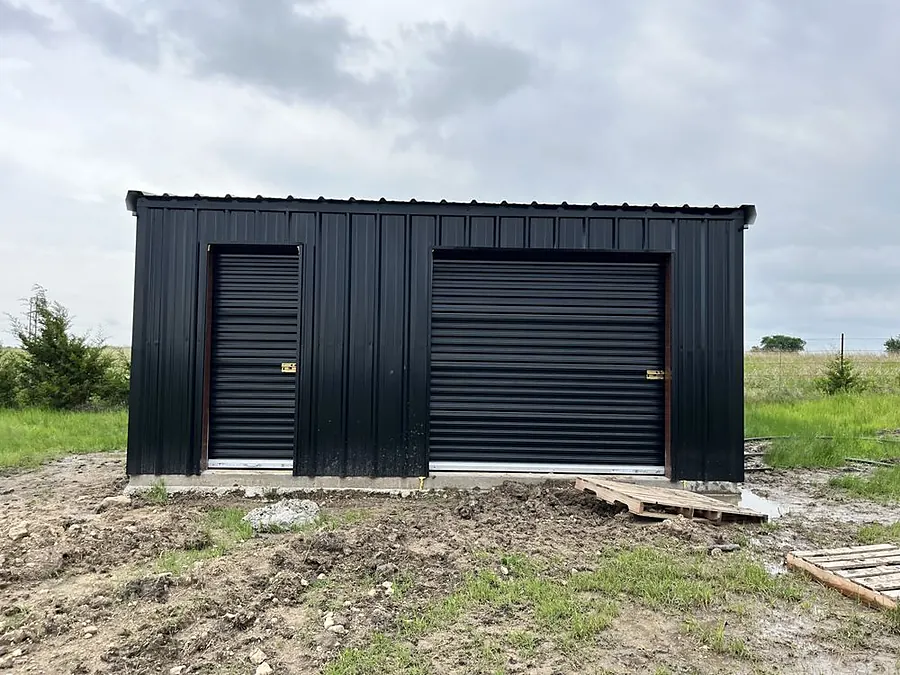 Commercial metal building with black roll-up garage doors and steel walk doors