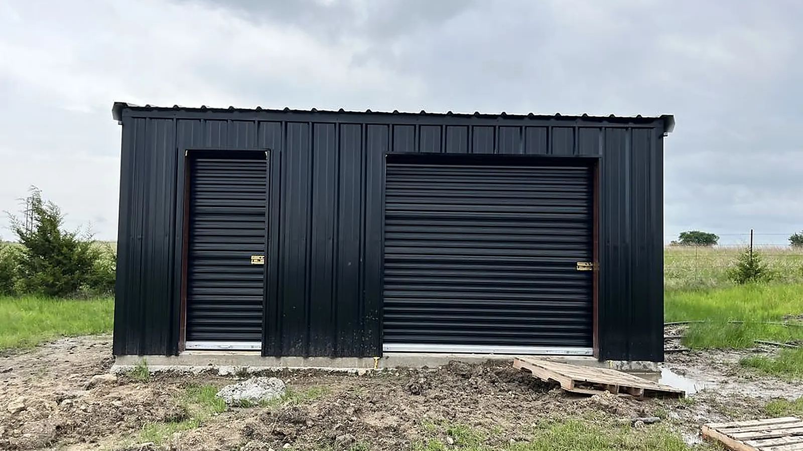 Commercial steel building with black roll-up garage doors and steel walk doors