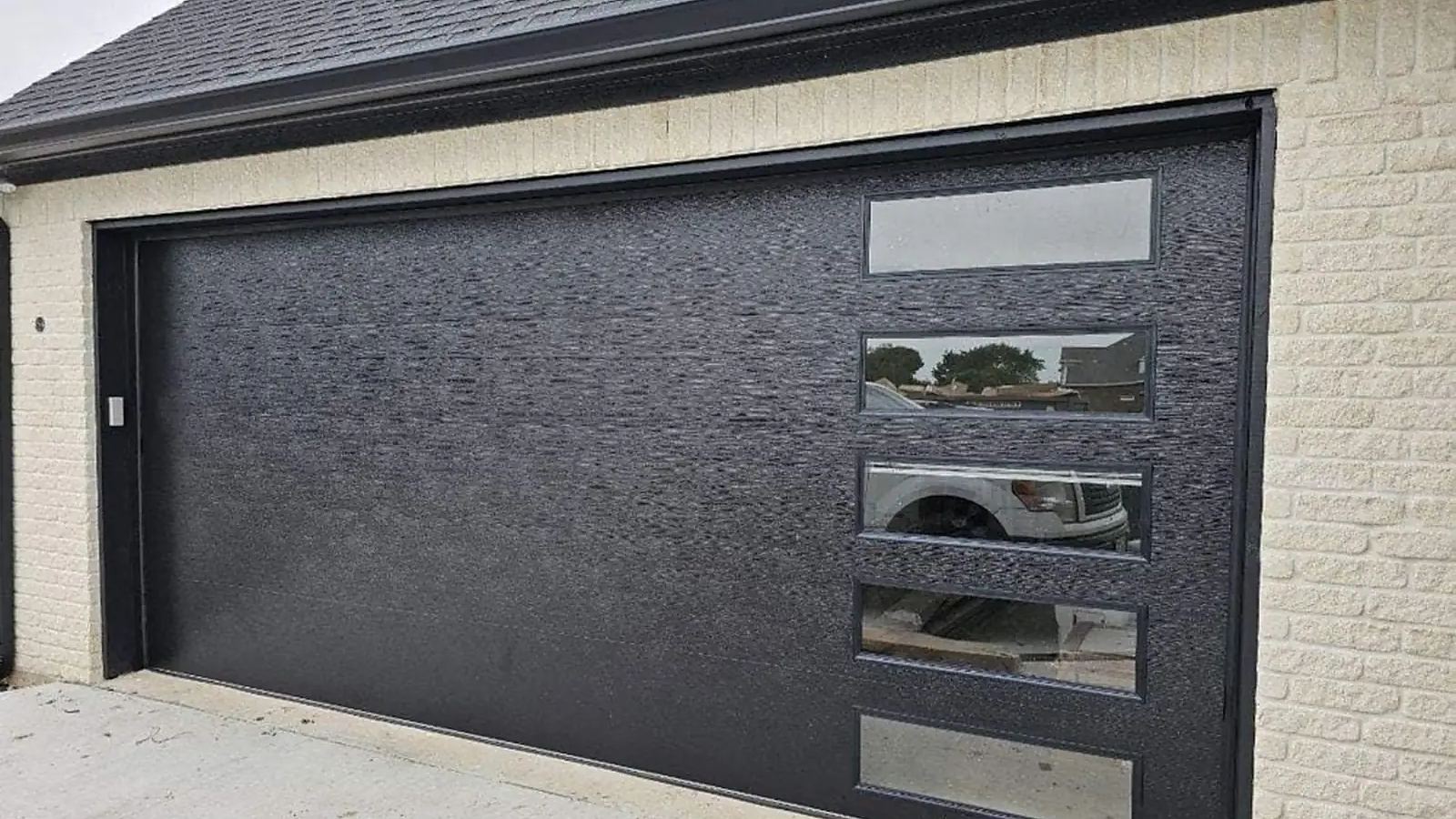 Black modern garage door with horizontal windows, secured after an emergency repair