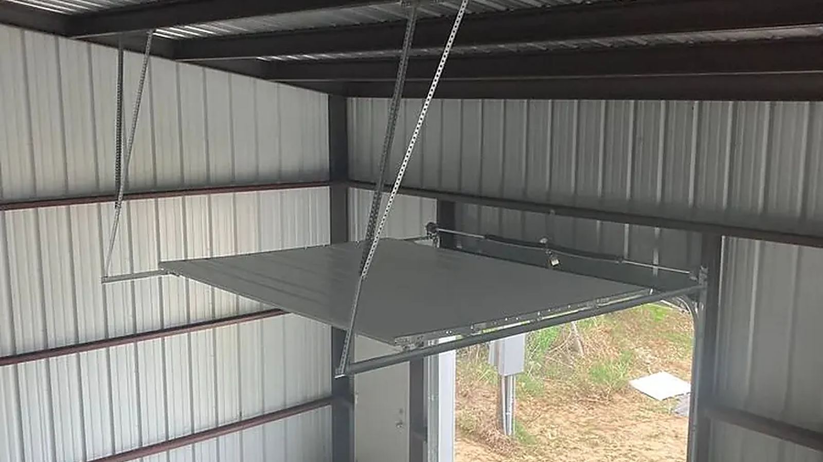 Torsion spring and opener rail area of a garage door being inspected during a spring repair